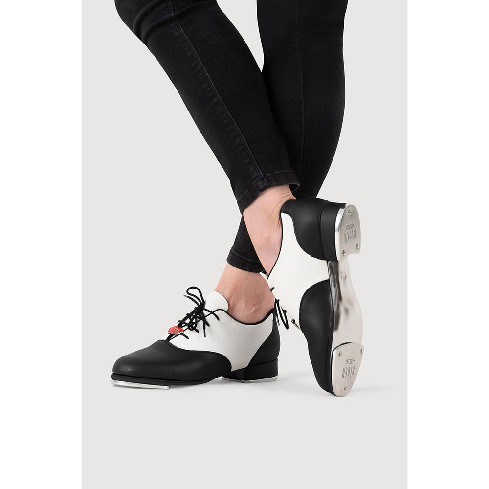 Black and white leather dance shoes with black laces, shown on a model's feet against a light gray background.