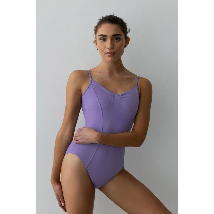 A woman modeling a lavender purple one-piece leotard or dance swimsuit against a plain light gray studio background.