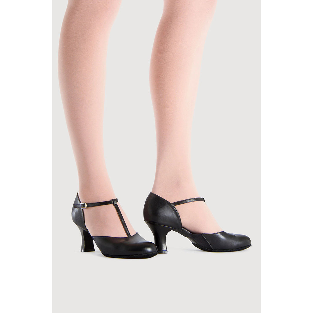 Black leather dance shoes with kitten heels and ankle straps, shown on a model&