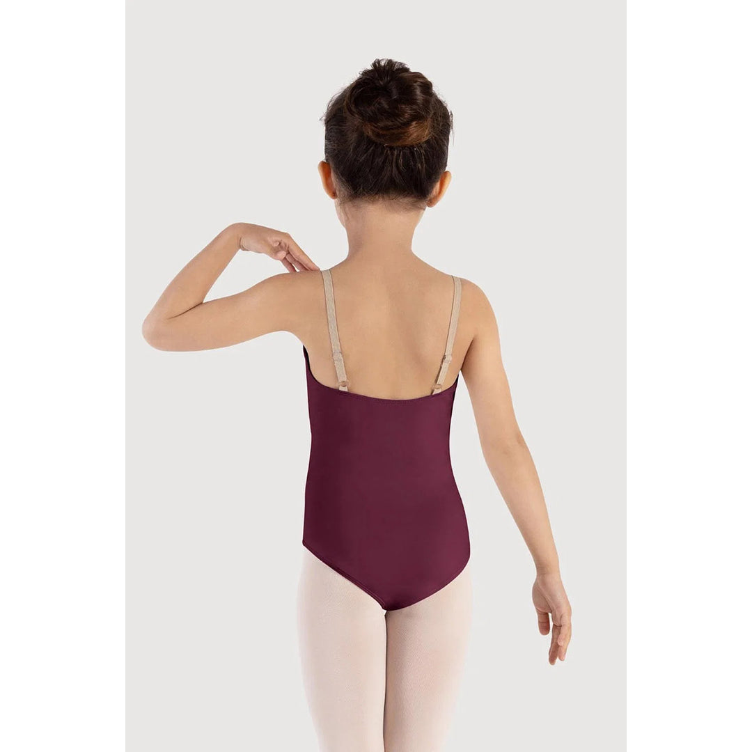 A child model shown from the back wearing a burgundy ballet leotard with beige shoulder straps and light pink tights, set against a plain light gray studio background.