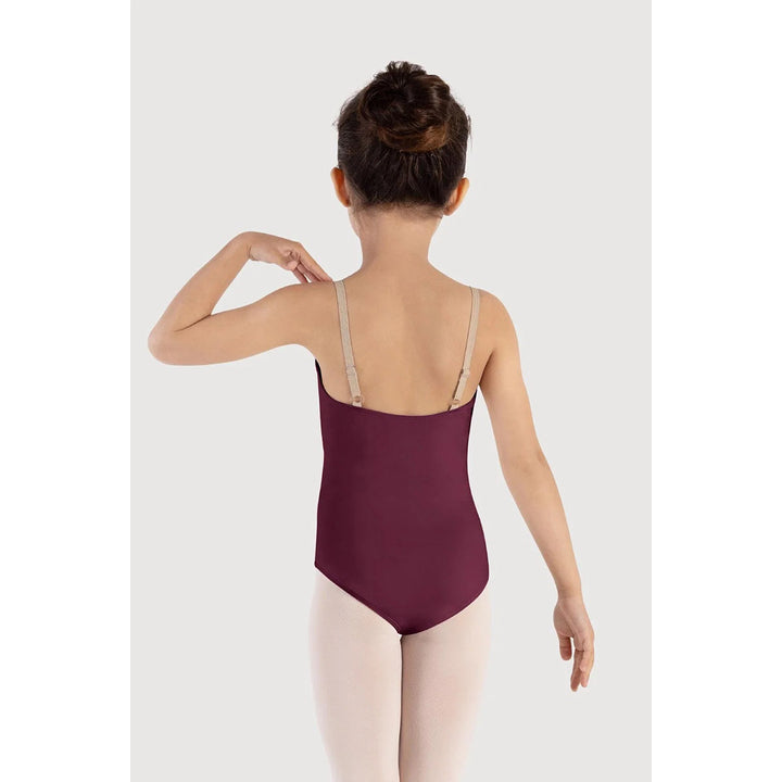 A child model shown from the back wearing a burgundy ballet leotard with beige shoulder straps and light pink tights, set against a plain light gray studio background.